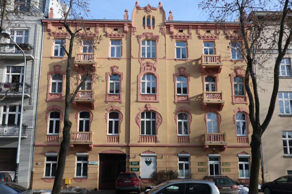 Odrestaurowana secesyjna elewacja kamienicy z ozdobnymi obramowaniami okien i różową sztukaterią, Plac Dąbrowskiego Łódź – RELIKT Konserwacja Zabytków